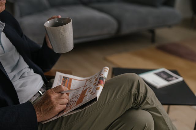 personne-en-pantalon-marron-lisant-un-journal